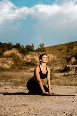 Gün batımında kadın yoga yapıyor ve çölde çivilerin üzerinde duruyor. Yoga ve çivilerin üzerinde durmak kavramı.