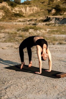 Gün batımında kadın yoga yapıyor ve çölde çivilerin üzerinde duruyor. Yoga ve çivilerin üzerinde durmak kavramı.