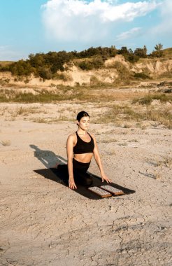 Gün batımında kadın yoga yapıyor ve çölde çivilerin üzerinde duruyor. Yoga ve çivilerin üzerinde durmak kavramı.