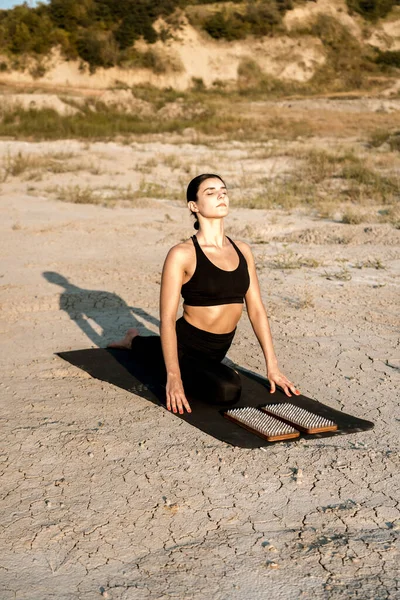 Woman doing yoga and standing on nails in the desert at sunset.The concept of yoga and standing on nails