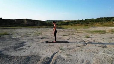 Gün batımında yoga yapan ve çölde çivilerin üzerinde duran bir kadın. Yoga ve çivilerin üzerinde durmak kavramı. Drone 4K çekti.