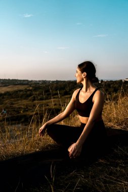 Gün batımında ağacın altında yoga yapan bir kadın. Yoga kavramı. 