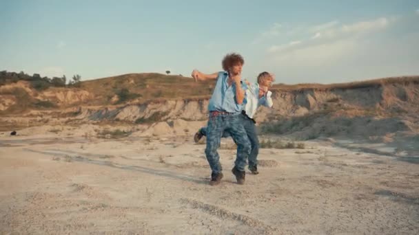 日落时两个小伙子在沙漠里跳现代舞 — 图库视频影像