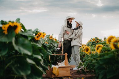 Genç arıcılar arılarla çalışır ve bal yerler. Genç bir arı yetiştiricisi ailesi ayçiçekli bir tarlada bal toplar. Bal toplama konsepti