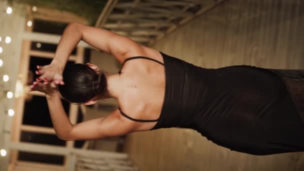 テラスで一人で黒いドレスでラティナダンスを踊るセクシーな女性 ダンスコンセプト 縦ビデオ — ストック動画