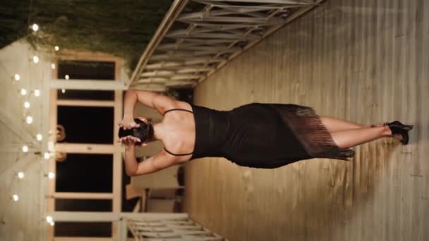 テラスで一人で黒いドレスでラティナダンスを踊るセクシーな女性 ダンスコンセプト 縦ビデオ — ストック動画