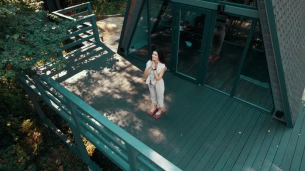 ある女性が森の家の近くのサドーボードに立っている 瞑想コンセプト ドローン映像 — ストック動画