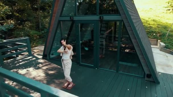 ある女性が森の家の近くのサドーボードに立っている 瞑想コンセプト ドローン映像 — ストック動画