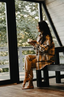 Bir kadın sonbaharda ormanda bir evde dinlenir ve meditasyon yapar. Geri çekilme ve meditasyon konsepti