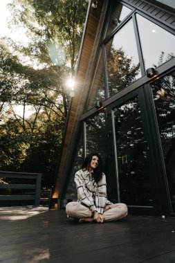 Bir kadın sonbaharda ormanda bir evde dinlenir ve meditasyon yapar. Geri çekilme ve meditasyon konsepti