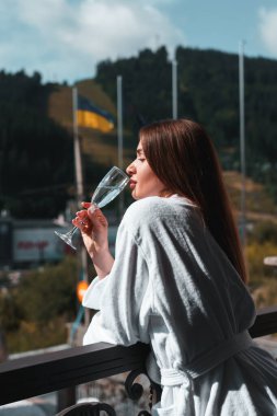 Bornozlu genç çiftin yakını otelin balkonunda, dağ arkasındalar.