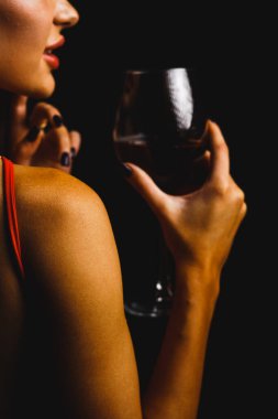 Kırmızı elbiseli seksi bir kadının ellerinde bir kadeh kırmızı şarap.