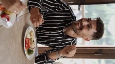 Birbirine aşık bir çift sabahları açık büfe sırasındaki bir restoranda kahvaltı eder. Otelde kahvaltı mı? Otelde rahatlama kavramı. Dikey video 
