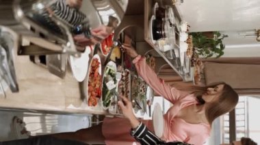 Birbirine aşık bir çift sabahları açık büfe sırasındaki bir restoranda kahvaltı eder. Otelde kahvaltı mı? Otelde rahatlama kavramı. Dikey video 