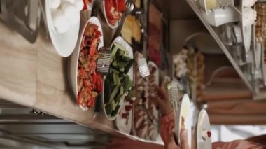 Birbirine aşık bir çift sabahları açık büfe sırasındaki bir restoranda kahvaltı eder. Otelde kahvaltı mı? Otelde rahatlama kavramı. Dikey video 