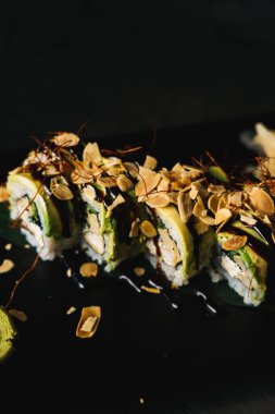 Siyah arkaplanda suşi. Siyah arka planda tepside taze rulo.