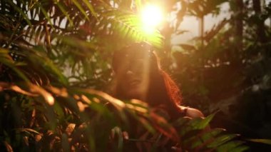 Palmiye ağaçlarının arasında tropik bir bahçede poz veren BDSM kedi maskeli seksi kadın. BDSM kavramı 44k