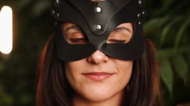 Palmiye ağaçlarının arasında tropik bir bahçede poz veren BDSM kedi maskeli seksi kadın. BDSM kavramı 44k