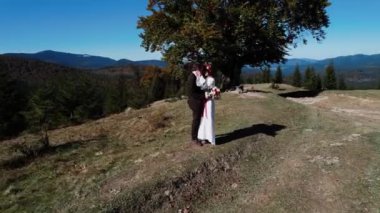 Otantik düğün çifti sonbaharda gün batımında dağlarda yürüyor. Düğün konsepti dağlarda. Sinema sahnesi 4K.