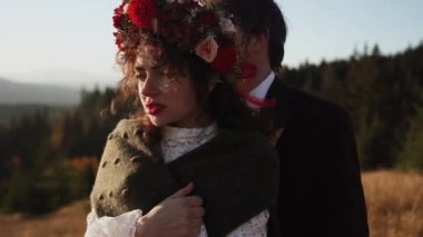 Otantik düğün çifti sonbaharda gün batımında dağlarda yürüyor. Düğün konsepti dağlarda. Sinema sahnesi 4K.