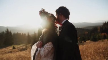 Otantik düğün çifti sonbaharda gün batımında dağlarda yürüyor. Düğün konsepti dağlarda. Sinema sahnesi 4K.