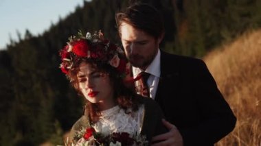Otantik düğün çifti sonbaharda gün batımında dağlarda yürüyor. Düğün konsepti dağlarda. Sinema sahnesi 4K.