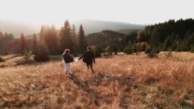 Otantik düğün çifti sonbaharda gün batımında dağlarda yürüyor. Düğün konsepti dağlarda. Sinema sahnesi 4K.