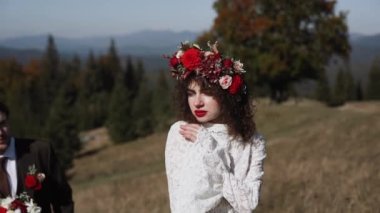 Otantik düğün çifti sonbaharda gün batımında dağlarda yürüyor. Düğün konsepti dağlarda. Sinema sahnesi 4K.