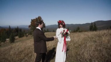 Otantik düğün çifti sonbaharda gün batımında dağlarda yürüyor. Düğün konsepti dağlarda. Sinema sahnesi 4K.