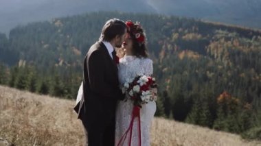 Otantik düğün çifti sonbaharda gün batımında dağlarda yürüyor. Düğün konsepti dağlarda. Sinema sahnesi 4K.