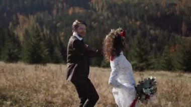 Otantik düğün çifti sonbaharda gün batımında dağlarda yürüyor. Düğün konsepti dağlarda. Sinema sahnesi 4K.