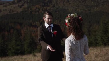 Otantik düğün çifti sonbaharda gün batımında dağlarda yürüyor. Düğün konsepti dağlarda. Sinema sahnesi 4K.