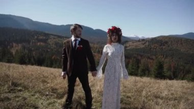 Otantik düğün çifti sonbaharda gün batımında dağlarda yürüyor. Düğün konsepti dağlarda. Sinema sahnesi 4K.