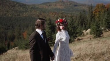 Otantik düğün çifti sonbaharda gün batımında dağlarda yürüyor. Düğün konsepti dağlarda. Sinema sahnesi 4K.
