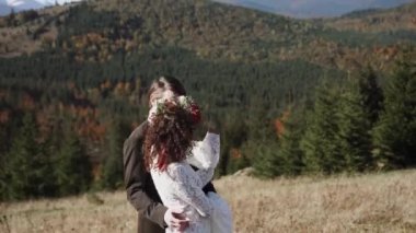 Otantik düğün çifti sonbaharda gün batımında dağlarda yürüyor. Düğün konsepti dağlarda. Sinema sahnesi 4K.