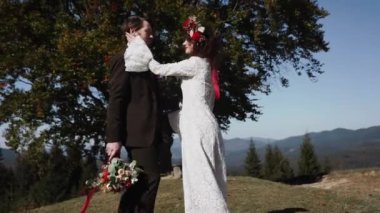 Otantik düğün çifti sonbaharda gün batımında dağlarda yürüyor. Düğün konsepti dağlarda. Sinema sahnesi 4K.