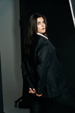 Profesyonel bir fotoğraf stüdyosunda siyah takım elbise ve beyaz gömlek içinde şık bir kız. Moda çekim konsepti