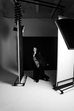 Profesyonel bir fotoğraf stüdyosunda siyah takım elbise ve beyaz gömlek içinde şık bir kız. Moda çekim konsepti