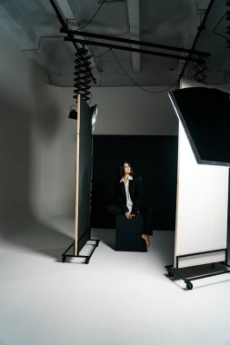Profesyonel bir fotoğraf stüdyosunda siyah takım elbise ve beyaz gömlek içinde şık bir kız. Moda çekim konsepti