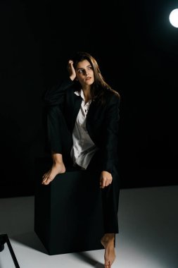 Profesyonel bir fotoğraf stüdyosunda siyah takım elbise ve beyaz gömlek içinde şık bir kız. Moda çekim konsepti