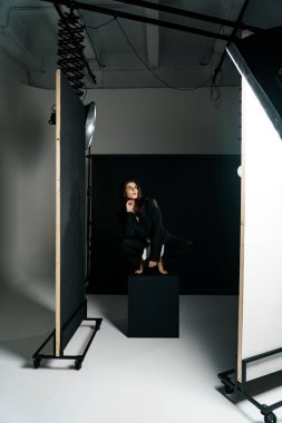 Profesyonel bir fotoğraf stüdyosunda siyah takım elbise ve beyaz gömlek içinde şık bir kız. Moda çekim konsepti