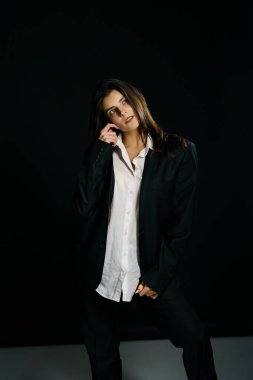 Profesyonel bir fotoğraf stüdyosunda siyah takım elbise ve beyaz gömlek içinde şık bir kız. Moda çekim konsepti