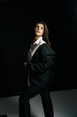 Profesyonel bir fotoğraf stüdyosunda siyah takım elbise ve beyaz gömlek içinde şık bir kız. Moda çekim konsepti