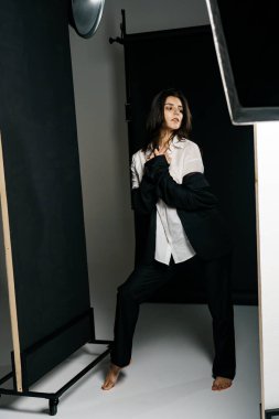 Profesyonel bir fotoğraf stüdyosunda siyah takım elbise ve beyaz gömlek içinde şık bir kız. Moda çekim konsepti