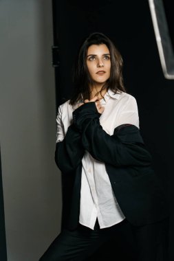 Profesyonel bir fotoğraf stüdyosunda siyah takım elbise ve beyaz gömlek içinde şık bir kız. Moda çekim konsepti