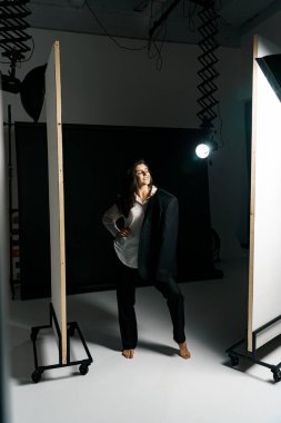 Profesyonel bir fotoğraf stüdyosunda siyah takım elbise ve beyaz gömlek içinde şık bir kız. Moda çekim konsepti