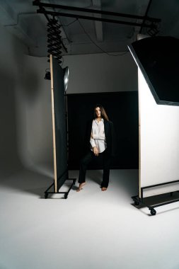 Profesyonel bir fotoğraf stüdyosunda siyah takım elbise ve beyaz gömlek içinde şık bir kız. Moda çekim konsepti