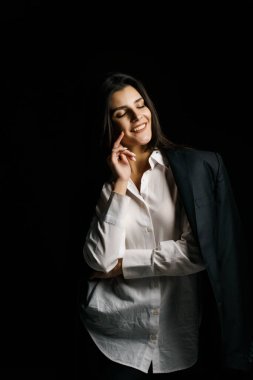 Profesyonel bir fotoğraf stüdyosunda siyah takım elbise ve beyaz gömlek içinde şık bir kız. Moda çekim konsepti