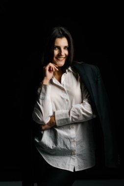 Profesyonel bir fotoğraf stüdyosunda siyah takım elbise ve beyaz gömlek içinde şık bir kız. Moda çekim konsepti