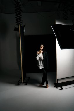 Profesyonel bir fotoğraf stüdyosunda siyah takım elbise ve beyaz gömlek içinde şık bir kız. Moda çekim konsepti